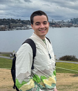 Photo of Noah Falcon hiking with a lake and city in the background